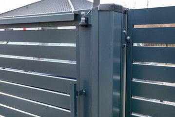 Modern sliding entrance gate in anthracite color, visible upper guide rollers.