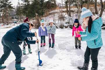 Fototapeta na wymiar ワカサギ釣り　全面結氷した湖に穴をあける小学生