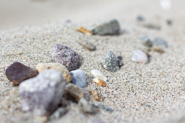 Sand mountain on the beach full of stones, blurry sea, and sand background. a pile of nice beach sand with and stones