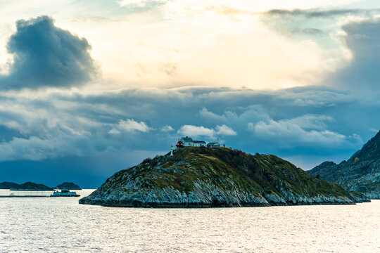 Bj&oslash;rn&oslash;y lighthouse, Leuchtturm vor der Insel Landegode bei Bod&oslash;, Norwegen. Herbst im Norden, mit Sturmwolken und verschneite Berge. die Kreuzfahrt f&uuml;hrt an der felsigen K&uuml;ste entlang