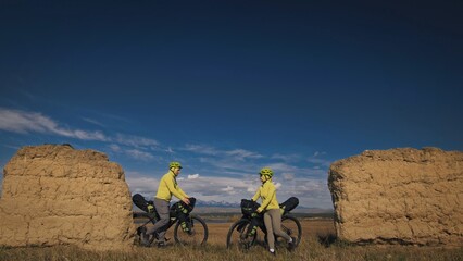 The man and woman travel on mixed terrain cycle bike touring with bikepacking. The two people...