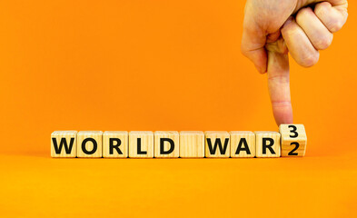 WW3 world war 3 symbol. Businessman turns the wooden cube and changes the concept word World War 2 to World War 3. Beautiful orange background, copy space. Business WW3 world war 3 concept.