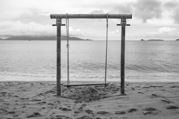 Chairs hanging on bamboo rails on the beach, black and white tones