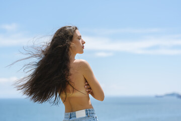 Naklejka premium Beautiful adult woman enjoy sea on sunny day. View from back.