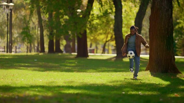 Happy father playing football in sunny park alone. Smiling player having fun.