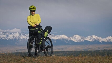 The woman travel on mixed terrain cycle touring with bikepacking. The traveler journey with bicycle...