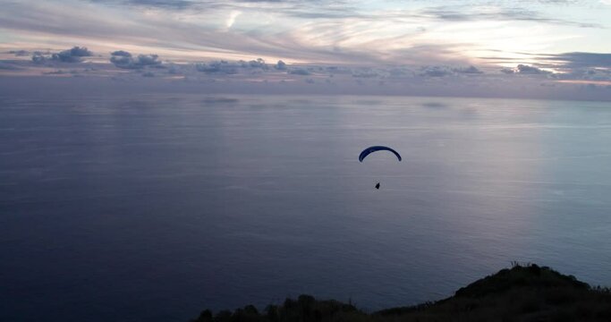 Drone above the mountains and the sea at sunset with a paraglider