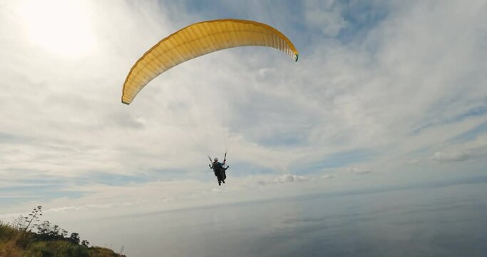 FPV drone over the mountains and the sea following a paraglider