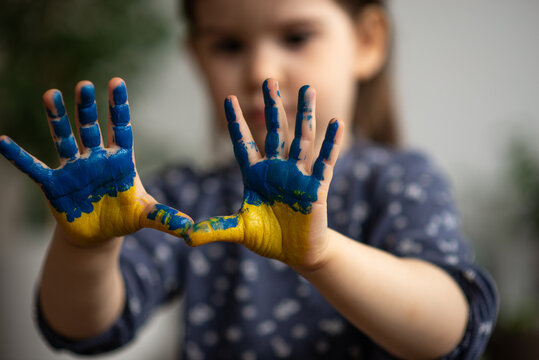 Little girl with hands in paints Ukrainian flag symbolic