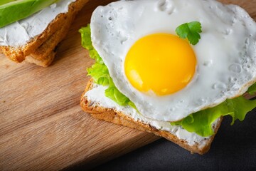 Sandwiches with curd cheese, fried egg, avocado and herbs