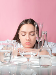 A beautiful young brunette among glasses of clean water, the benefits of clean water for beauty and health, concept. Parts of the face are refracted in a glass of water