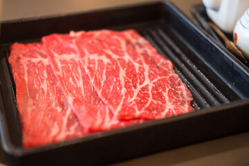 Fresh beef raw sliced with marbled texture served on black tray