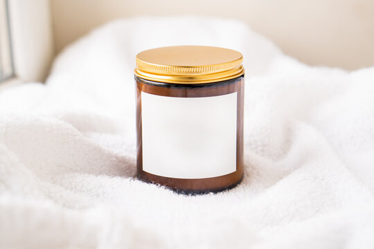 Amber glass jar with metal lid and blank label on white cotton fabric background