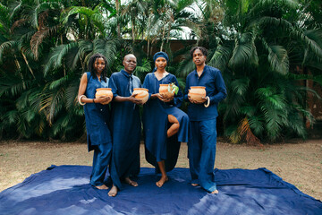 Wide angle portrait of group of african eco fashion designers standing together in nature