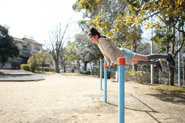 Obraz premium 公園の鉄棒で遊ぶ女の子