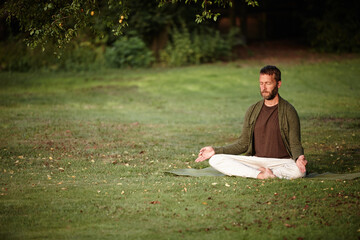 Naklejka na ściany i meble Finding peace of mind in nature. Shot of a handsome mature man meditating in the lotus position in the outdoors.