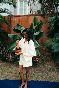portrait of a african woman holding pestle and mortar in nature
