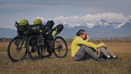 The man and woman travel on mixed terrain cycle touring with bikepacking. The two people journey...