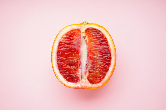 Juicy blood orange and condensed milk on a pink background, top view. Sex concept 18+