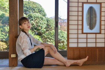 古民家の和室に座りくつろぐ若くスリムな美しい女性	