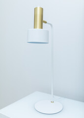 Vertical shot of white table lamp in a modern style with a top painted in gold color