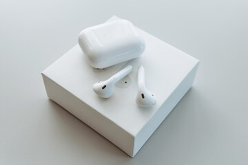 White wireless bluetooth headphones or headphones, plastic case or storage and charging box lie on...