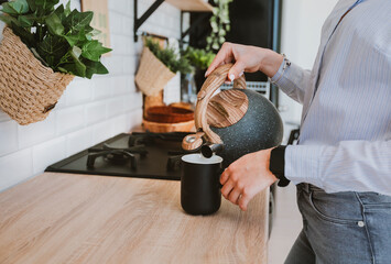 girl pours tea from a kettle in the kitchen