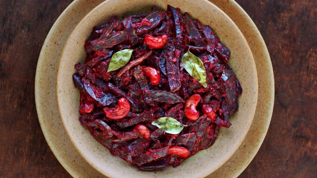 Grated beetroot curry with coconut and cashews. Indian cuisine top view table spin zoom-in.