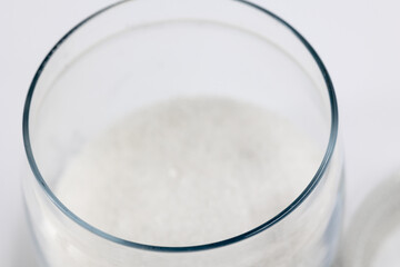 Blurred white refined granulated sugar in a transparent glass jar top view close-up