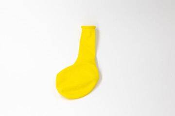 One bright yellow inflatable uninflated colored balloon for the holiday lies on a white background isolated
