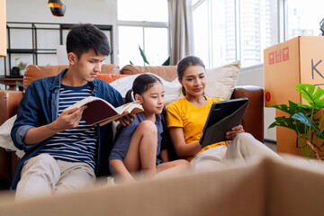 moving home concept,asian family relax leisure time sit together with cardboard box and stuff,dad mom  daughter spending time together after finish packing stuff furniture for home apartment moving