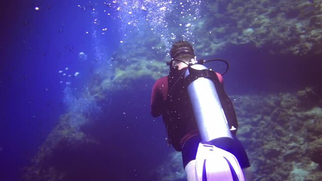 underwater view of diver with camera shot another diver on bottom of coral reef.