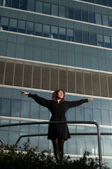 Fototapeta premium girl with arms outstretched and wind in her face, body buried against the backdrop of a glass-fronted building facade
