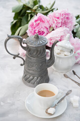 vintage still life with a cup of coffee against a bouquet of pink peonies 