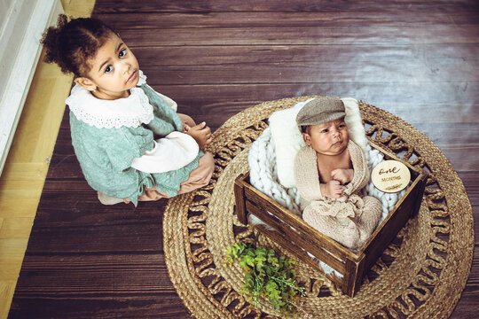 Little mixed-race sister sitting next to her baby brother in a photoshoot