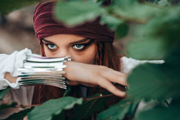 Portrait of young female in pirate costume peaking through branches