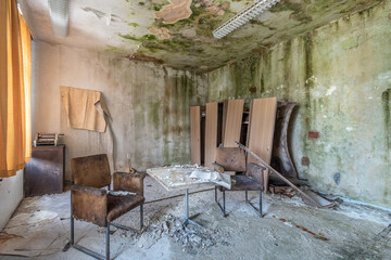 Old abandoned and run-down room in a hotel with destroyed chairs, table and closet