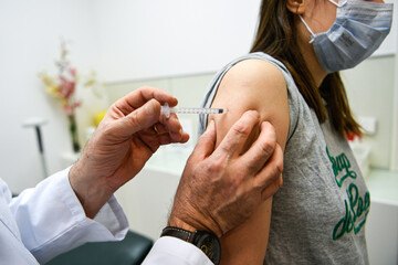 Vaccination illustration, a general practitioner holds a syringe with a vaccine close to the arm of a patient he is vaccinating