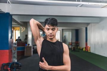 A young man does single arm tricep extensions with a kettlebell. Feeling the stretch of his...