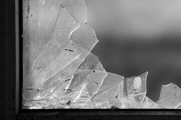 Shards of glass in the window after the bombing of houses in Kharkov, the ruins of buildings. Russian military aggression against Ukraine, war. Black and white shot.