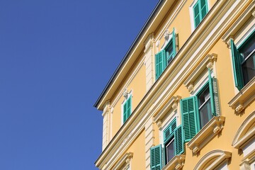stylish building with shutters, sea wooden shutters, yellow tenement house, decorations and ornaments on the facade of the building, blue sky