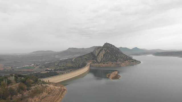 Aerial images showing a huge reservoir from 120 meters high.  In the background a large mountain with a medieval castle on it.  Camera pans to the right showing more reservoir  Faster.