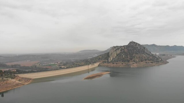 Aerial images showing a huge reservoir from 120 meters high.  In the background a large mountain with a medieval castle on it.  Camera continues panning to the right showing more reservoir