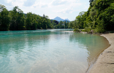 calm turquoise river Lech by Fuessen in Bavaria on a sunny summer day with the Alps in the background (Germany)