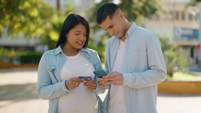 Young latin couple smiling confident using smartphone and credit card at park