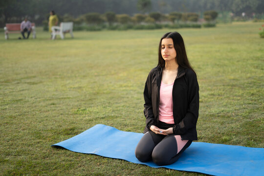 Young indian girl meditating in the park, early in the morning, yoga in the morning is a must. Healthy lifestyle and sports concept.