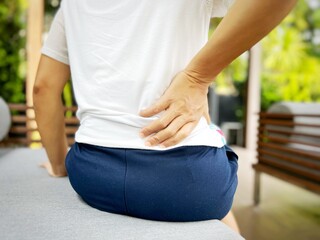 Thai asian woman with lumbar pain, backache and massage on waist to pain relief.