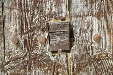 puerta pared de madera antigua vieja marrón agrietada con clavos metálicos y remiendos 4M0A3301-as22 - obrazy, fototapety, plakaty