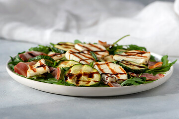 Light salad of young zucchini, bacon, halloumi cheese with arugula.