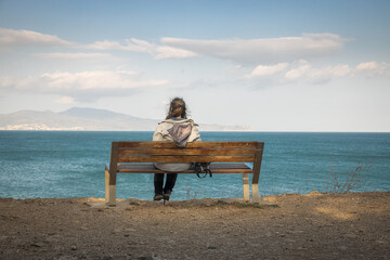 Woman sitting on a bench looking relaxed at the sea on the Costa Brava